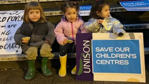 Save Hackney's Children's Centres Children hold up campaign placards saying "Save our children's centres"