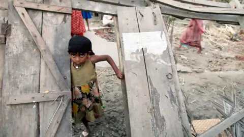 Getty Images A Bangladeshi cyclone-affected girl is framed with her destroyed house's door