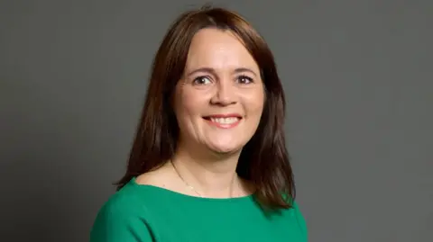 UK Parliament Portrait of Lindsay Farnsworth - she has brown hair and is wearing a green dress