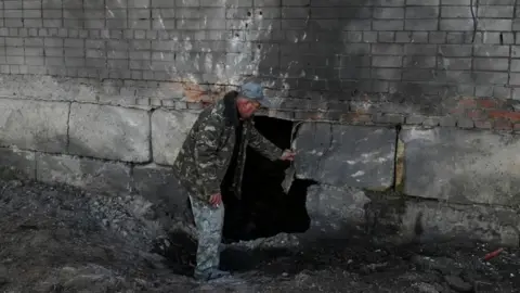 Reuters A resident inspects his apartment building hit by a Russian drone strike, amid Russia's attack on Ukraine, in the village of Krasylivka, Chernihiv region, Ukraine, 3 November 2024