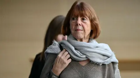 Getty Images Headshot of a woman with a short brown bob, wearing a grey scarf and a grey V-neck jumper