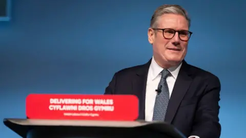 Getty Images Sir Keir Starmer behind a podium reading Delivering for Wales