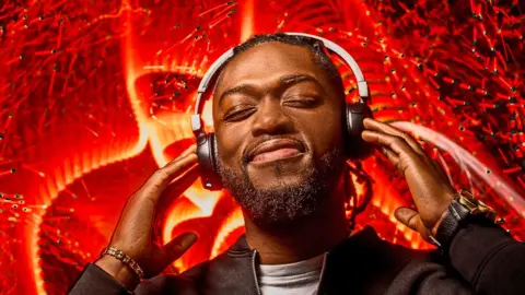 Getty Images A man wearing headphones with red lighting effects behind him