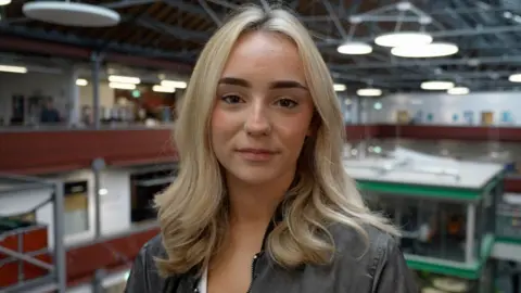 BBC News Hannah, a sixth-form student, looks into the camera. She has long blonde hair and is wearing a dark grey jacket.