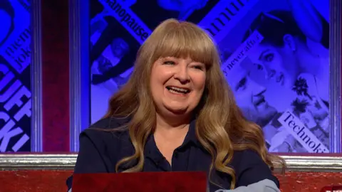 BBC Janey Godley, who has long wavy brown hair and a navy blue blouse, on the panel of Have I Got News For You