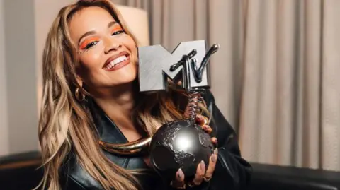 MTV Rita Ora holding up an MTV Award trophy