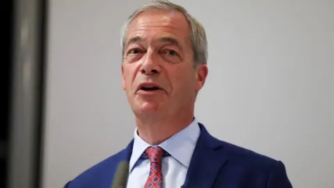 Reuters A head and shoulders picture of Nigel Farage speaking to the media in London in July, wearing a blue suit, light blue short and a tie with blue spots and red stripes