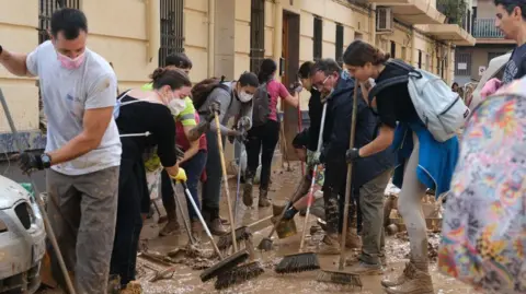 Getty Images Volunteers with brushes attempt to clear mud in Valencia 