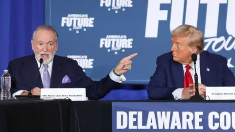 Reuters File photo showing Mike Huckabee (L) and Donald Trump (R) sitting in front of a sign saying America's Future Tour at a campaign event in Drexel Hill, Pennsylvania, US on 29 October 2024