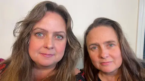 BBC two green-eyed women looking into the camera. They are identical twins and although they have styled their long hair differently, the similarity in their faces is still evident