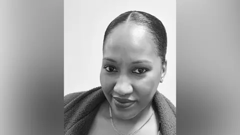 Courtesy of Jeanell Hippolyte A black and white selfie of a woman with her hair in a bun and wearing a chain necklace